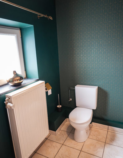 Salle de bain/douche styles art déco. Décoration dans les tons vert et doré avec des motifs géométriques.